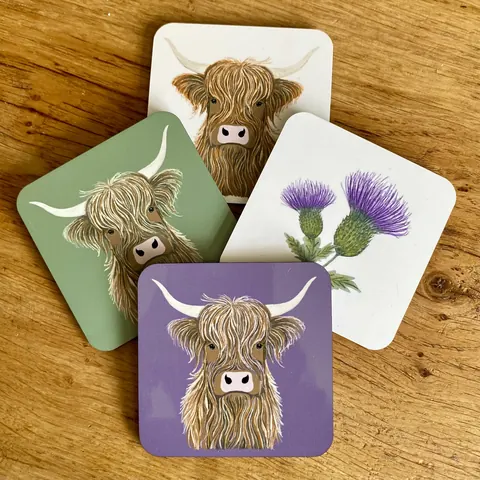 A group of four coasters with a cow on them.