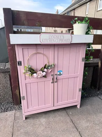 A pink kitchen cupboard with a sign on it.