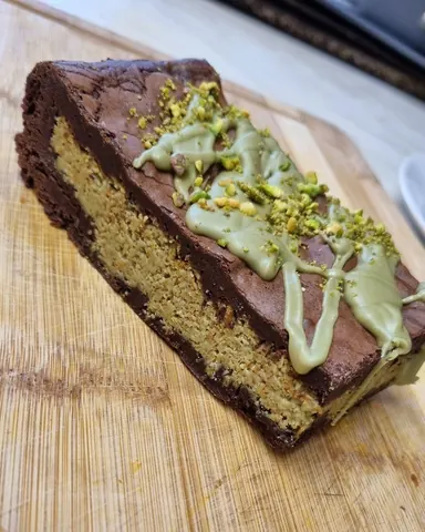 A piece of cake with green toppings on a wooden table.