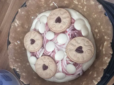 A bowl of cookies with white frosting and red hearts.