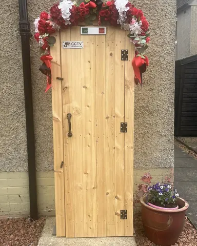 A wooden door with a red ribbon and flowers on it.
