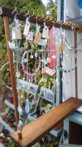 A collection of beads and charms hang from a wooden frame.