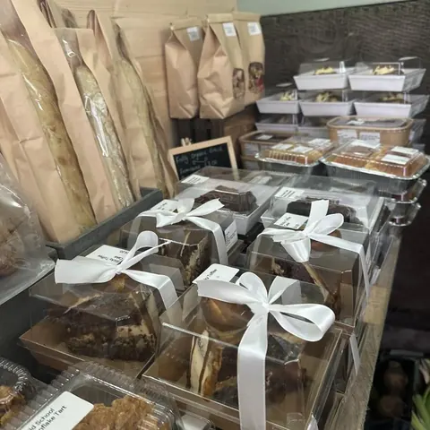 A table full of food, including cakes and pastries, is displayed in a store.