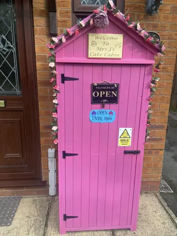 A pink door with a sign that says Welcome.