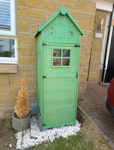 A green shed with a window and a door.