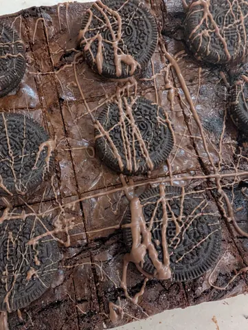 A chocolate cake with chocolate drizzle and Oreo cookies on top.