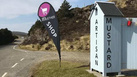 A sign for a shop is on the side of a road.