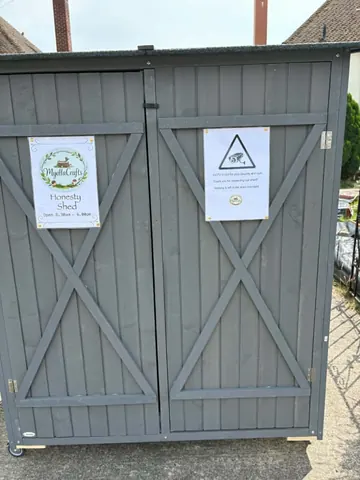 A gray shed with a sign that says "honesty" on it.