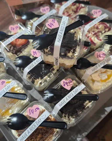 A collection of desserts in plastic containers with forks sticking out of them.