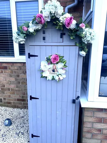 A blue door with a white flower wreath on it.