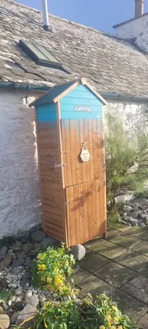 A blue and white wooden shed with a sign on it.
