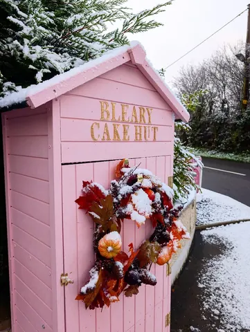 A pink shed with a sign that says "Blair Cake Hut" on it.