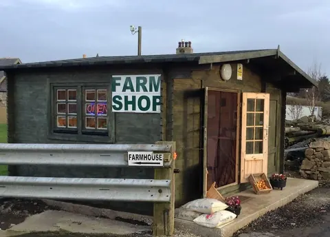 A small wooden building with a sign that says "farm shop" on it.