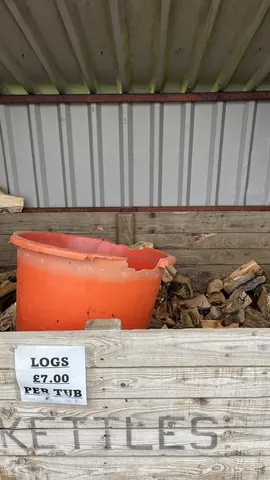 A large orange bucket is sitting on a pile of wood.