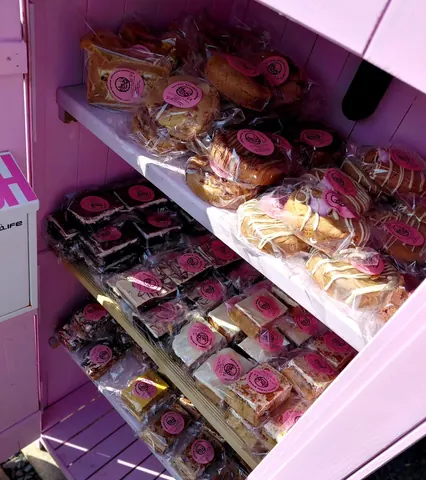 A pink shelf with a variety of food items on it.