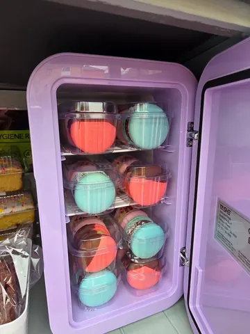 A purple refrigerator with a drawer full of colorful balls.