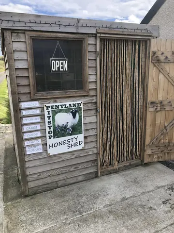 A small wooden building with a sign that says "Open" on it.