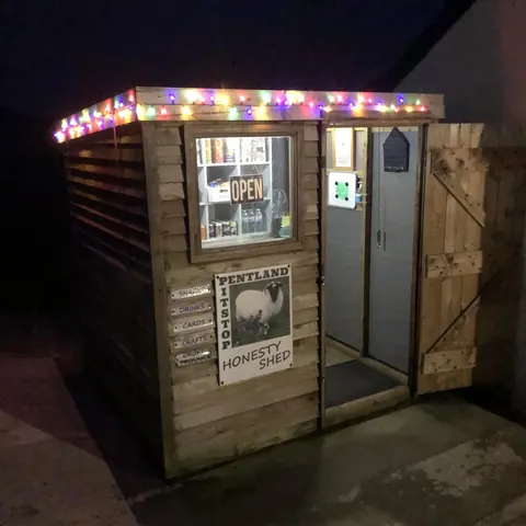A small wooden building with a sign that says "honesty sheep" on it.