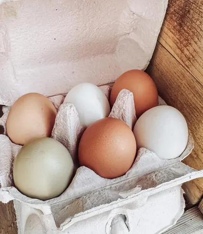 A carton of eggs is sitting on a wooden table.