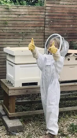 A young girl wearing a white suit and yellow gloves is giving a thumbs up.