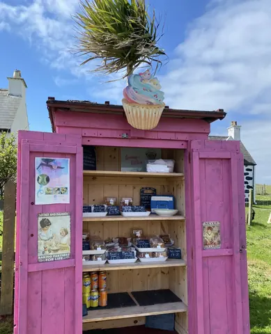 A pink building with a cupcake holder on top.