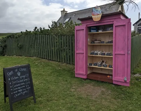 A pink shed with a sign that says "cafe" in front of it.
