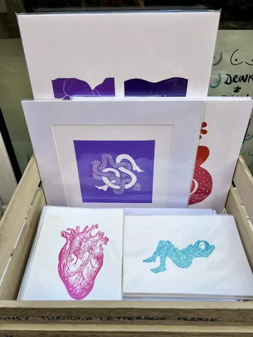 A stack of artwork with a heart and a snake on it.