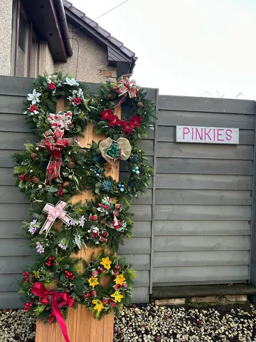 A wooden fence with a sign that says "Pinkies" on it.