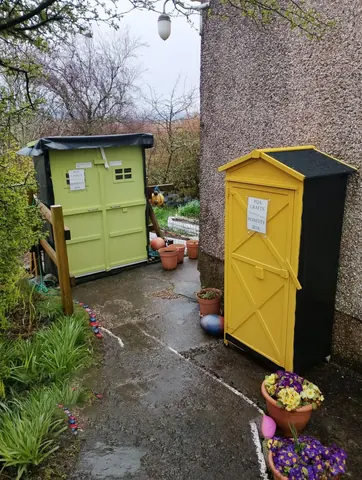 Two green and yellow sheds are sitting next to each other.