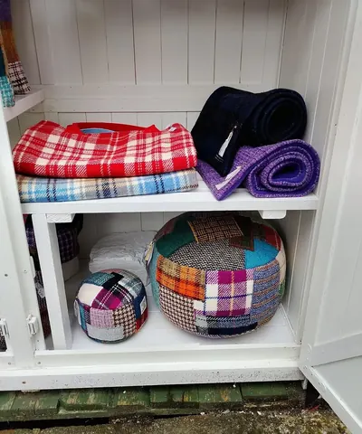 A white shelf with a blue and white blanket on it.