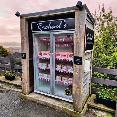 A small wooden building with a sign that says Rachael's.