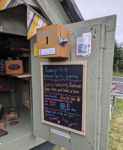 A chalkboard sign is on a green building.