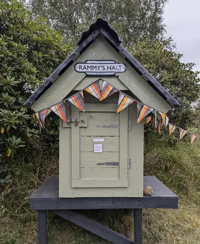 A small green building with a sign on it.