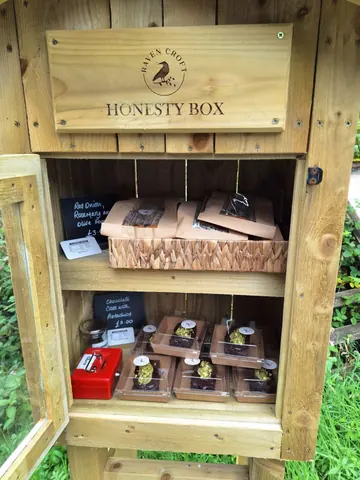 A wooden box with a red lid and a sign that says Honesty Box.