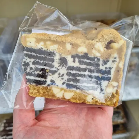 A hand holding a piece of cake.