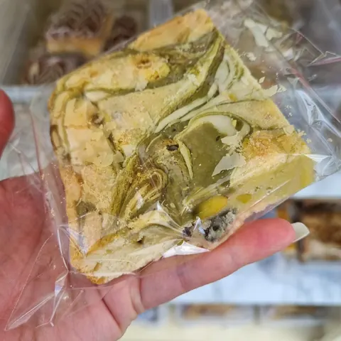 A hand holding a piece of food in a plastic bag.