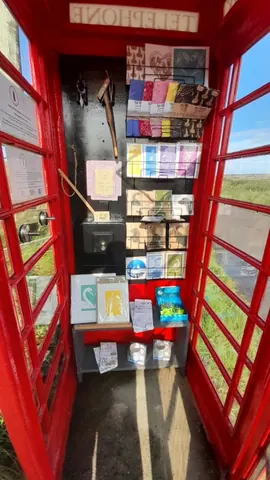 A red telephone booth with a sign that says "please do not touch" and a box of tissues.