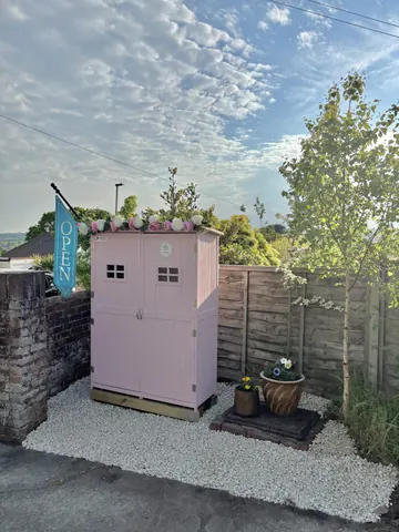 A pink shed with a sign that says "open" on it.