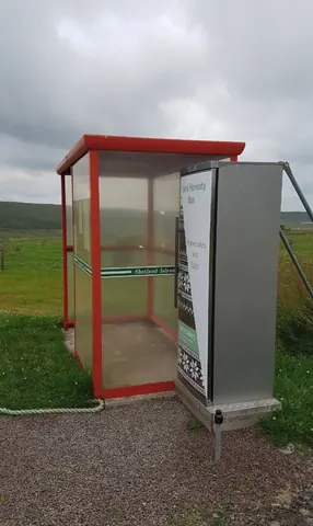 A red telephone booth with a sign on it.