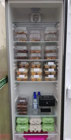 A refrigerator with a black cooler on the bottom.