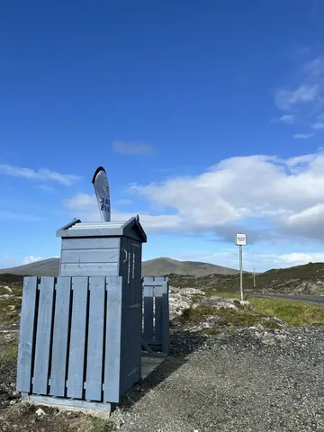 A blue and white shed with a surfboard on top of it.