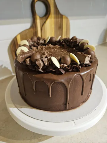 A chocolate cake with white frosting and chocolate chips.