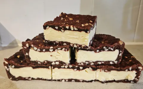 A stack of three cakes with chocolate and white frosting.