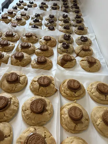A large number of cookies with chocolate chips on them.