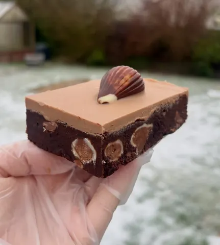 A piece of chocolate cake with a topping of a chocolate square and a chocolate square on top.