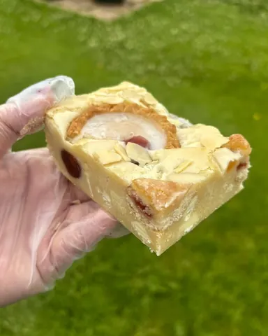 A hand holding a piece of cake.