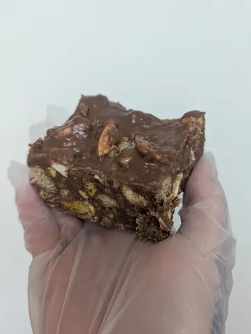 A hand holding a piece of chocolate cake.