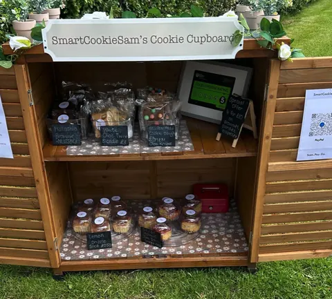 A wooden cupboard with a sign that says "Smart Cookies Sam's Cookie Cupboard".
