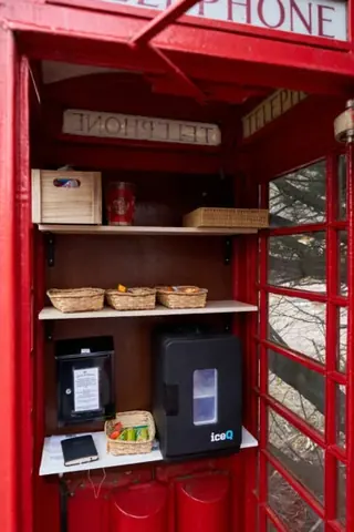 A red telephone booth with a black box inside.