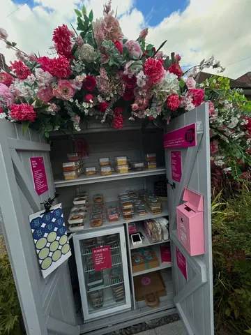 A small pink building with a sign that says "Flower Shop" on it.